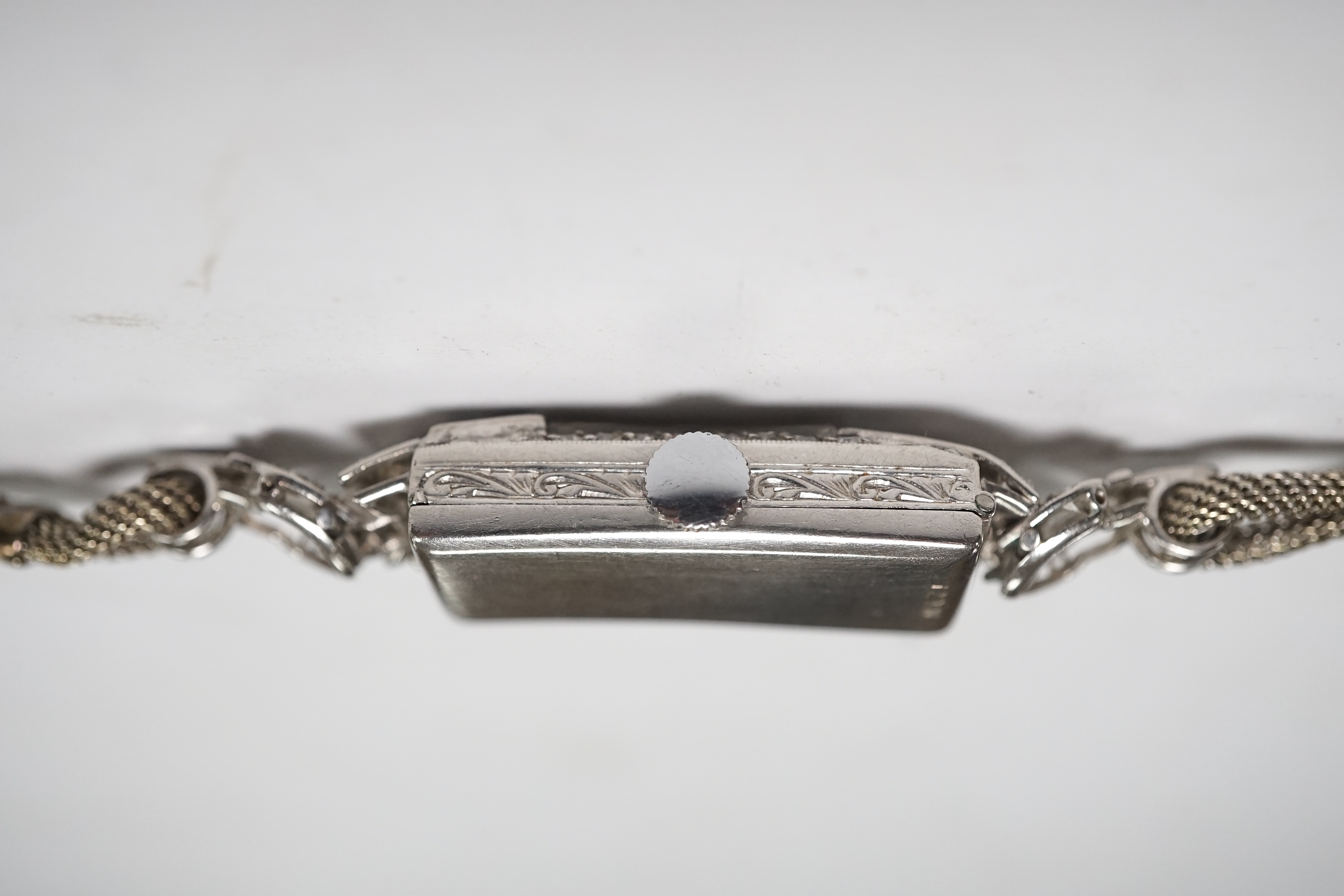 A lady's mid 20th century white metal (stamped platinum) and diamond set manual wind cocktail watch, on a 9ct white metal twin strand bracelet, overall length 16.5cm, gross weight 17.6 grams/ Condition - fair to good